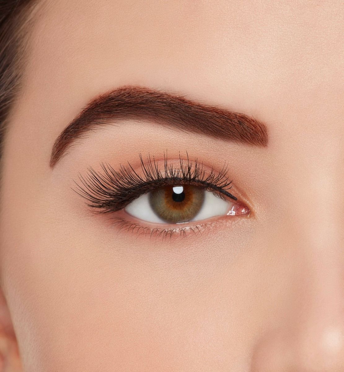 A model with one eye open wearing Ardell Aqua Lashes 341 upper false lashes to show how they look on the eye
